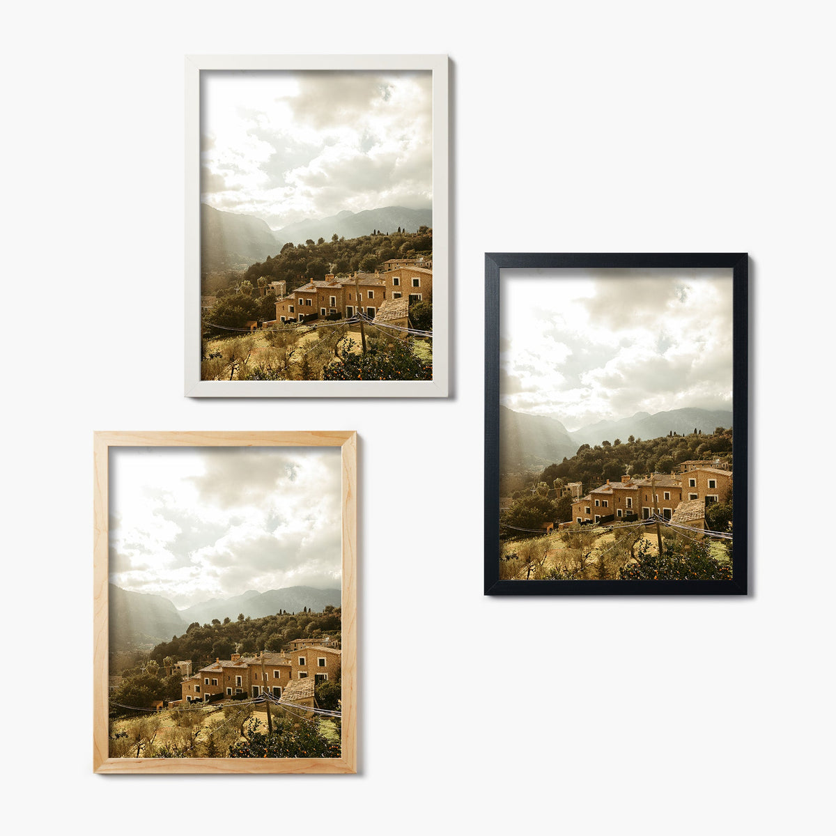 Three framed glass prints of a scenic landscape with buildings and mountains in the distance.
