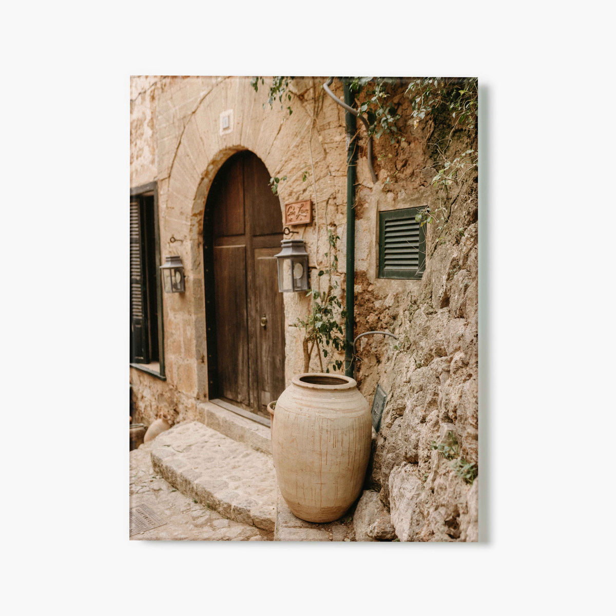 Glass Print of a stone archway with wooden door and large ceramic pot in a narrow alley.