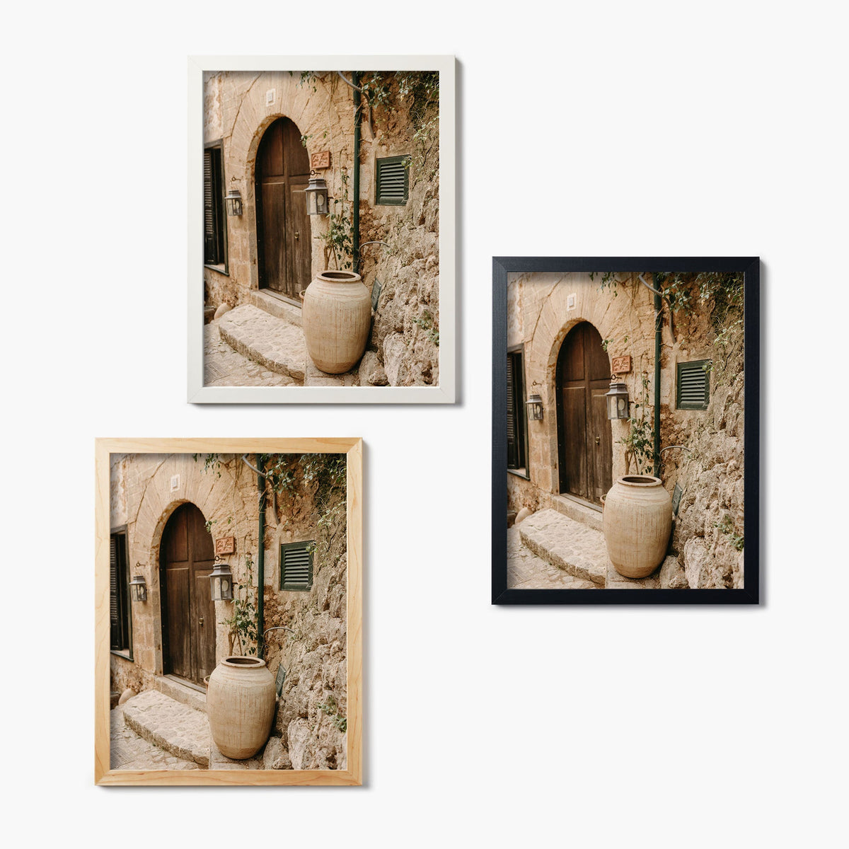 Three framed glass prints of a stone archway and wood door with a vase on a white background