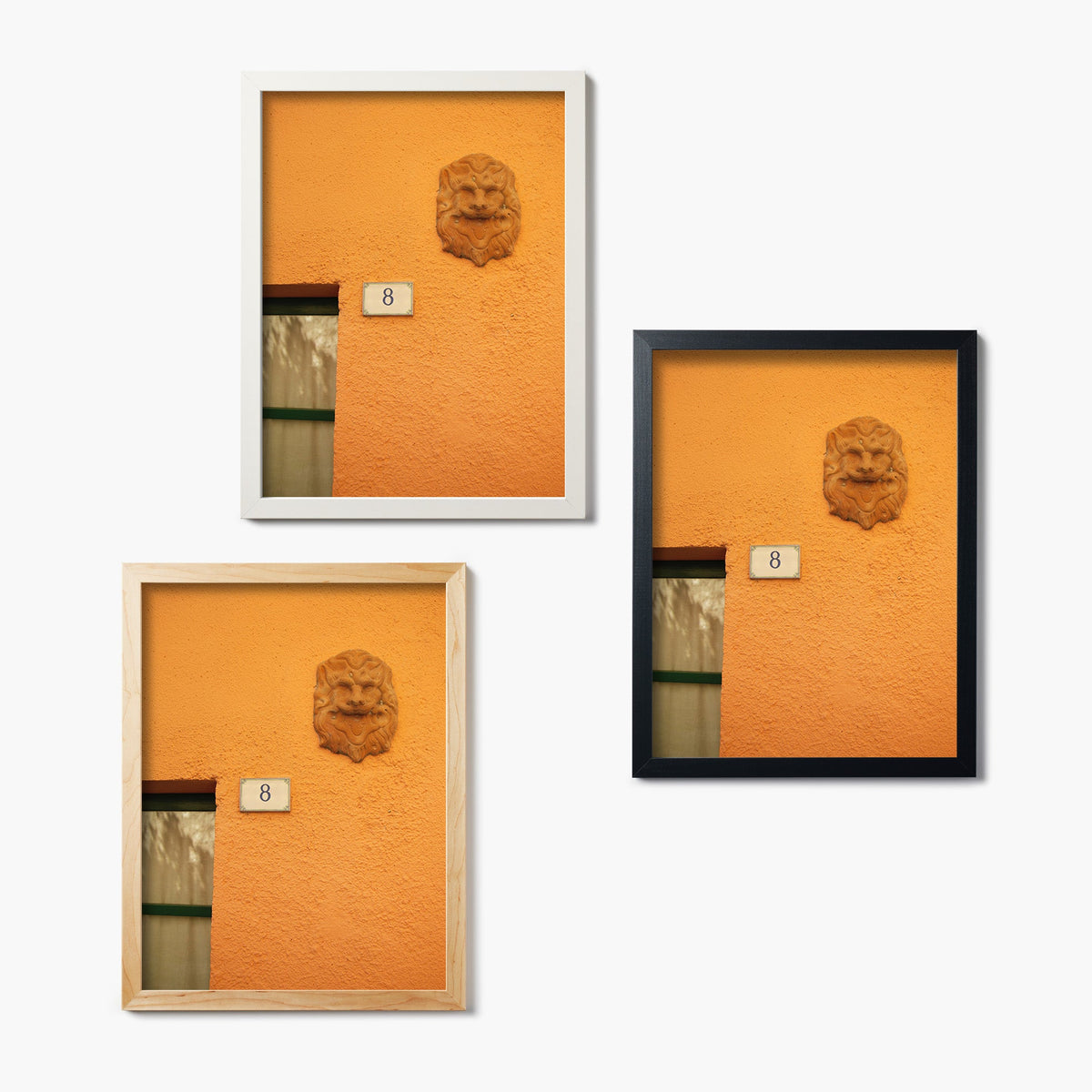 Three framed glass prints of an orange painted wall with a lion head statue and number 8 sign.
