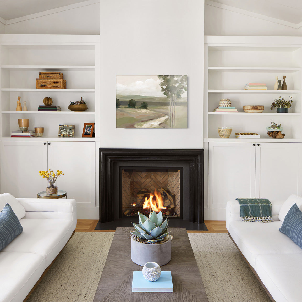 Living room with white walls, a fireplace, and a glass print of a painted landscape.