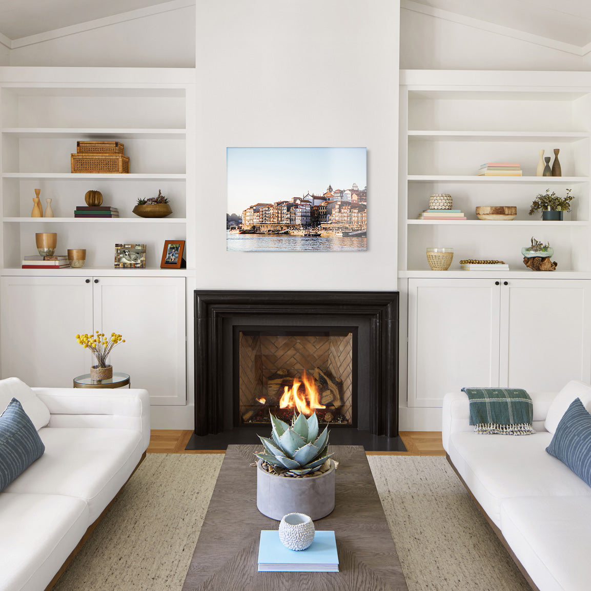 Modern living room with white walls, a fireplace, and a glass print of the Porto riverfront above the mantel.