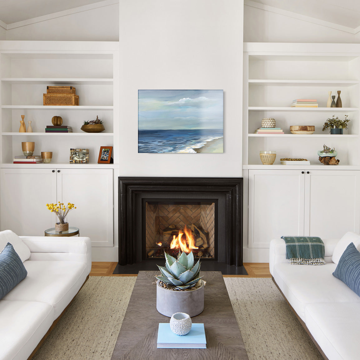Modern living room with white walls, a fireplace, and a glass print of a painted beach scene above the mantel