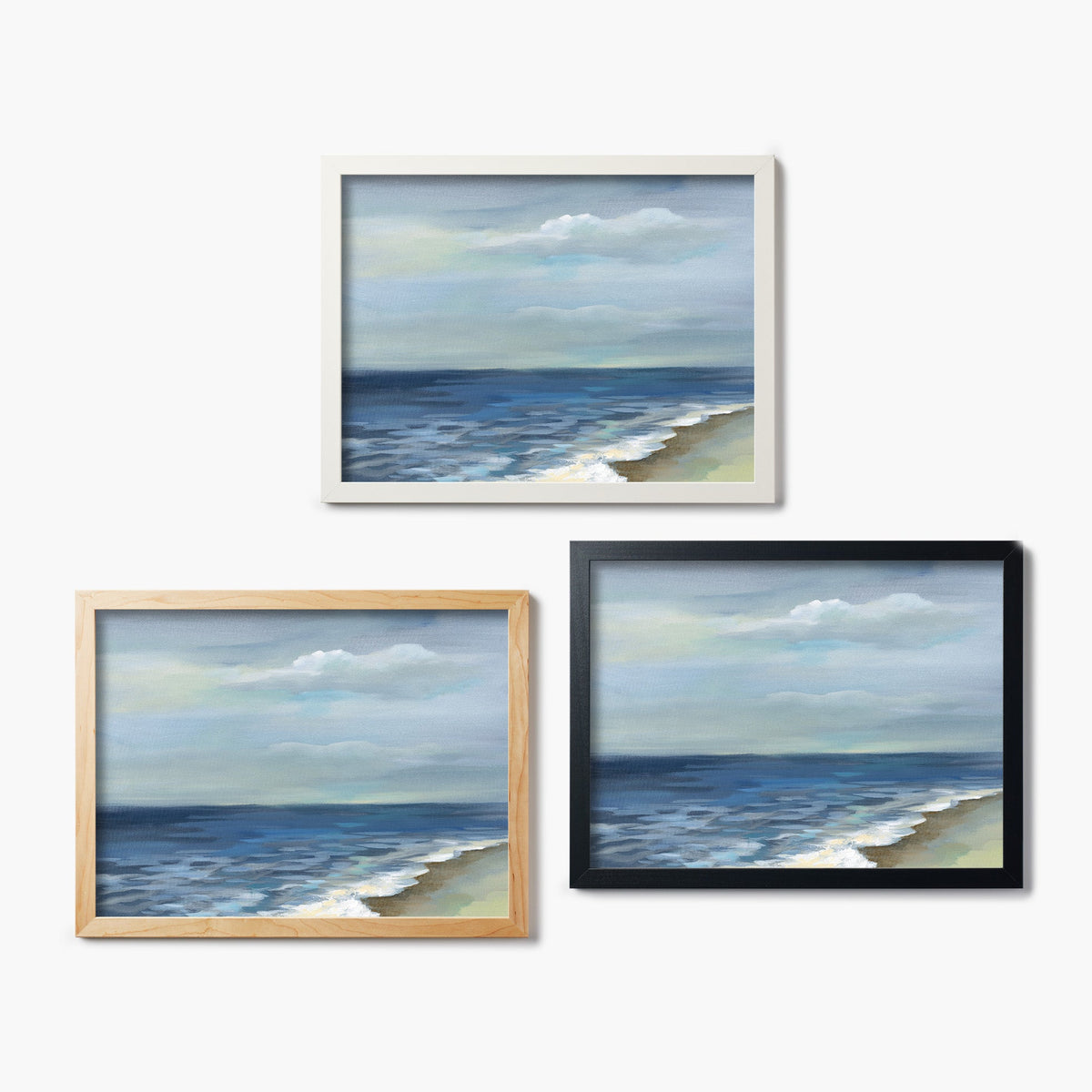 Three framed glass prints of a painting of a beach scene on a white background